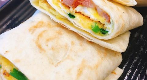 Breakfast burrito with eggs, ham, and green onions.