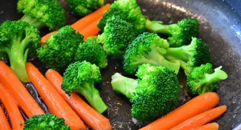 Skillet with broccoli and carrots being stir fried.