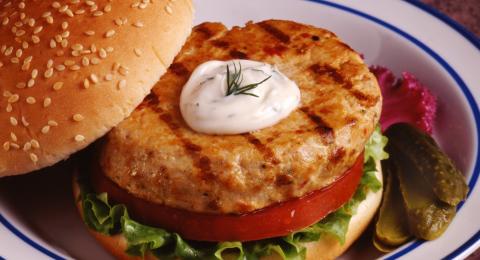 Alaskan salmon burger recipe prepared on a bun with lettuce and tomato.