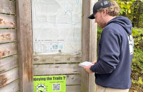 Ethan O'Leary viewing a trail map on a Keene Paths trail kiosk