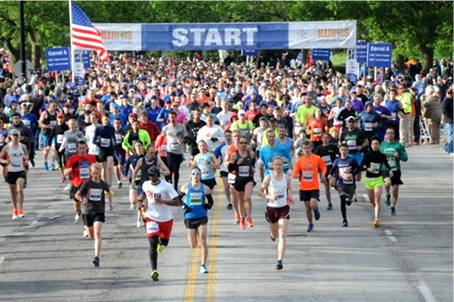 Several hundred marathon runners crossing under a large start banner