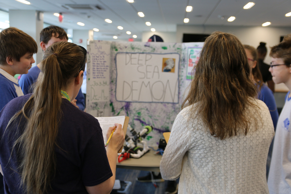 Judges at the Seacoast SeaPerch Challenge inspect posters about the vehicles.