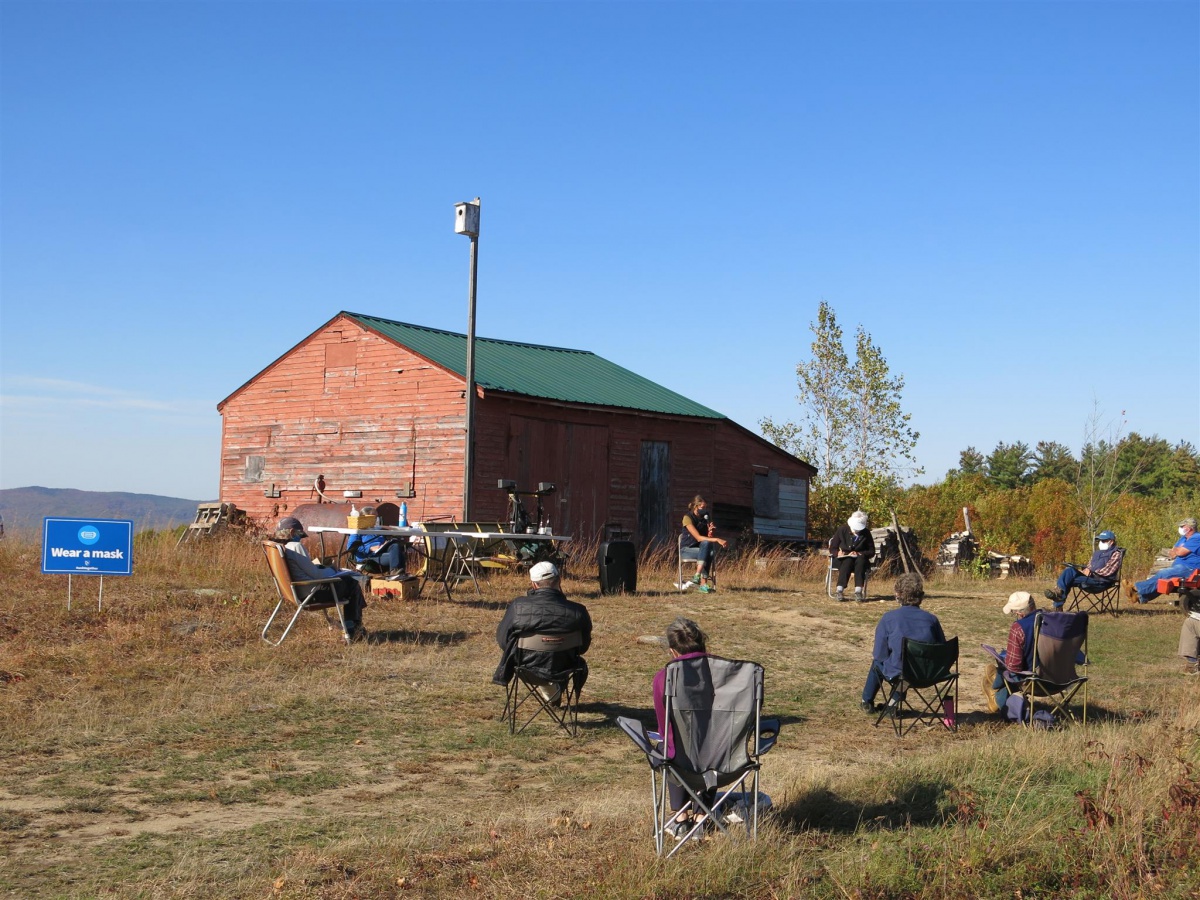 Participants sitting in chairs, wearing masks at outdoor meeting