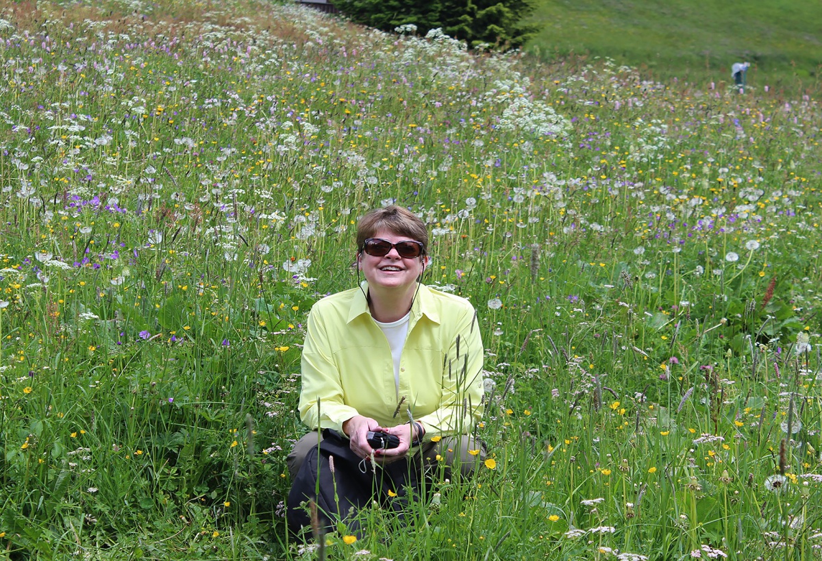 Sandra Pickering leaning down in a field of dandelions