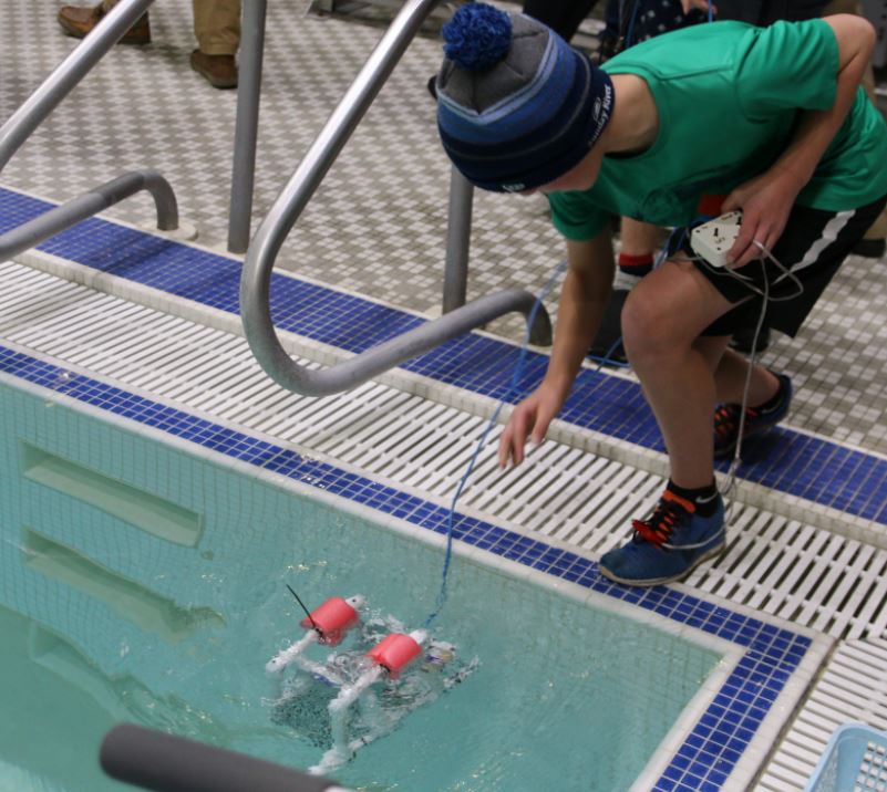 Student launching a SeaPerch underwater remote operated vehicle 
