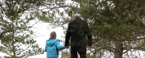 Grandfather walking in woods with granddaughter