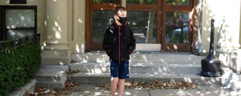 Boy wearing mask in front of school