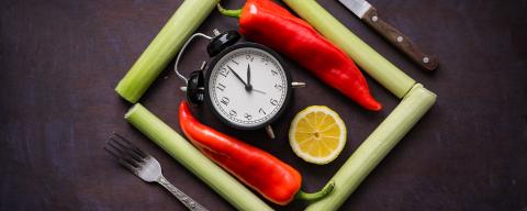 green onion, red chili peppers, lemon slice, fork, knife and alarm clock