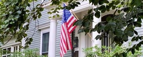 front door of a grey house with American flag