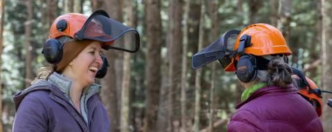 women laughing in the woods wearing hard hats