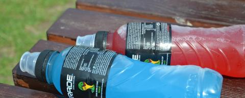 Two bottles of an electolyte type beverage one in the color red and the other in the color blue.
