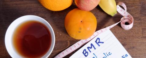Cup of tea with banana, orange, clementine, apple, tape mesure and paper that has BMR - Basal Metabolic Rate = 10m+6.25h-5a+5 m=weight(kg) h=height (cm) a=age s=sex male +5 femaole -161 