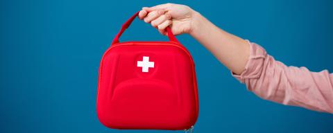 A hand holding a first aid kit
