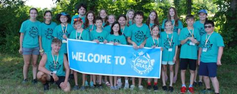 Group shot of campers outside holding up Camp ATLAS sign