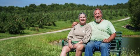 Woman and man sitting on bench in farm field