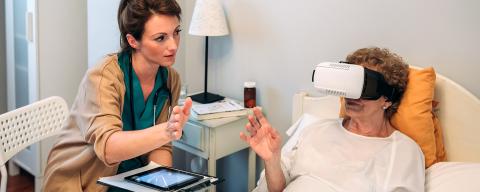 Nurse assisting older adult with VR technology in patient's room