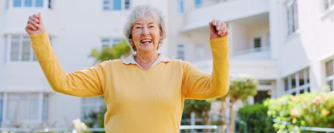 Elderly, female person smiling with celebration and full of energy at old age home, fresh air at park.