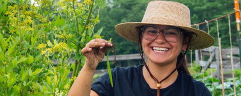 college student smiling in a garden with a bean