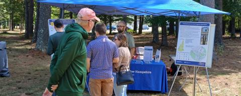 people gathered around a vendor tent viewing posters and table items