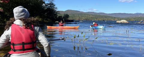 Shannon Rogers, in a red life vest, paddling a canoe on Lake Winnipesaukee
