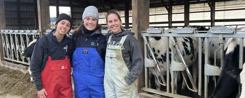 Three researchers in front of a dairy barn