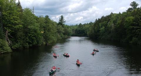Summer campers canoing down a river.
