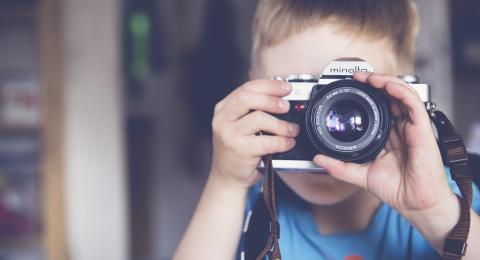 A boy looking througha camera lens.