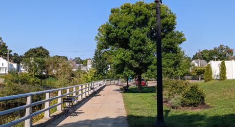 Shaded walkway path along river with bistro style seating.