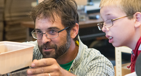 Man showing science experiment to student in classroom