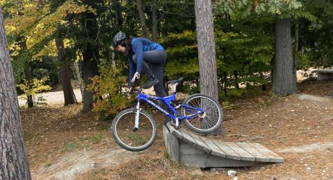 Maddie Smith navigating a wooden ramp on a mountain bike