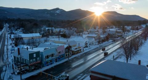 Aerial view of downtown village with snow covered buildings with the sun rising over distant mountains 