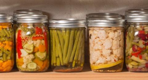 row of home canned vegetable and preserves in glass canning jars