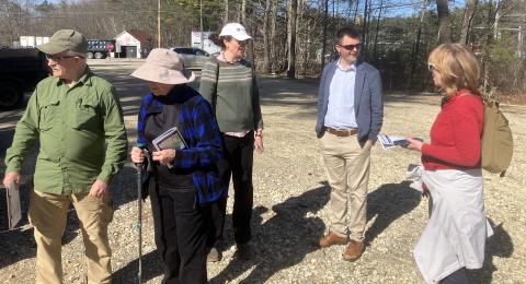a group of people standing in a gravel parking lot 