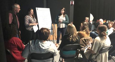 a group of people in conversation around a flip chart