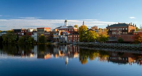 Reflections of brick buildings and fall foliage colors on a calm river