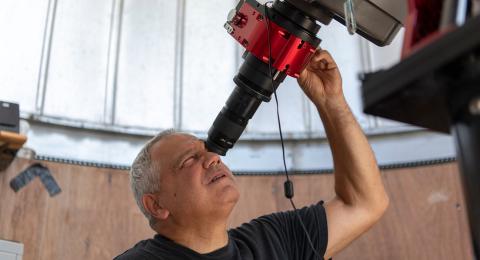 John Gianforte looks through a telescope to study astronomy in the UNH Observatory