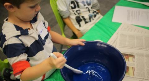 Child stirring Oobleck in a bucket