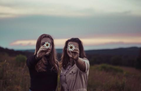 Young women holding up daisies