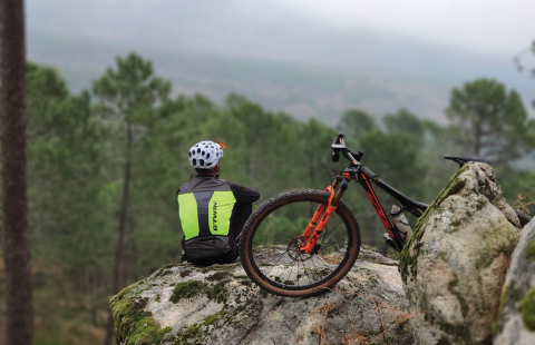 Biker sitting on mountain next to bike