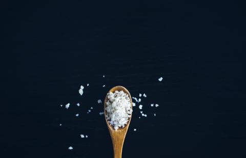 Wooden spoon filled with coarse salt.