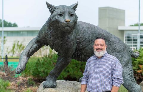 Man standing in front of wilcat statue