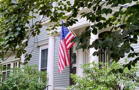 front door of a grey house with aAmerican flag
