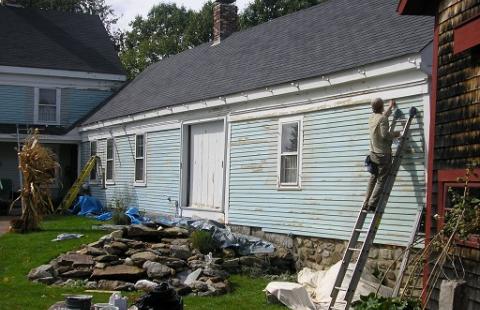 historic home with painter on ladder