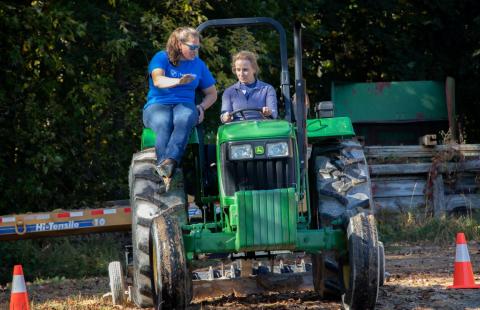 Woman driving tractor and receiving instructor from another woman