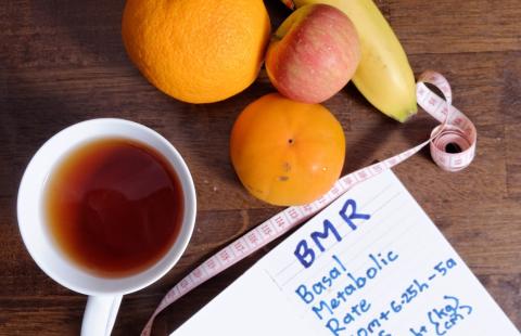 Cup of tea with banana, orange, clementine, apple, tape mesure and paper that has BMR - Basal Metabolic Rate = 10m+6.25h-5a+5 m=weight(kg) h=height (cm) a=age s=sex male +5 femaole -161 