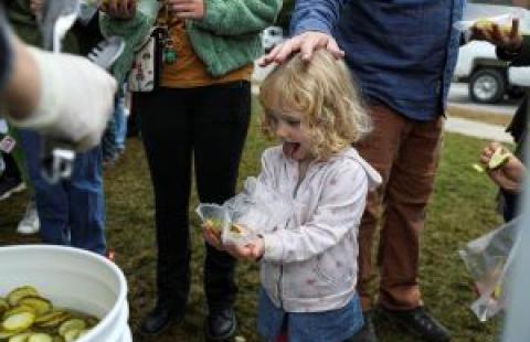 young blonde girl holding a bag of pickles