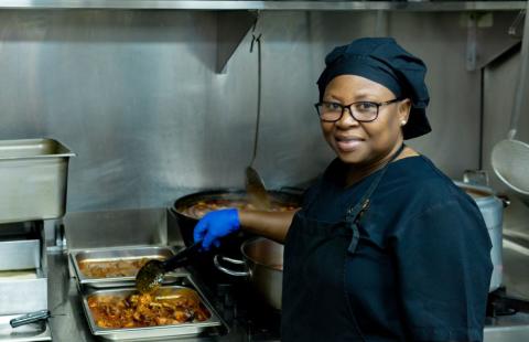 kitchen worker stirring food and smiling