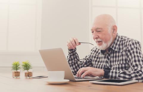 Smiling senior man using laptop.