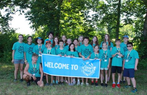 Group shot of campers outside holding up Camp ATLAS sign