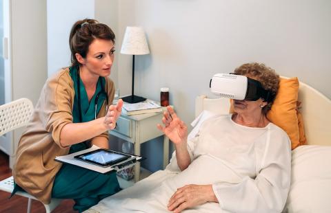 Nurse assisting older adult with VR technology in patient's room